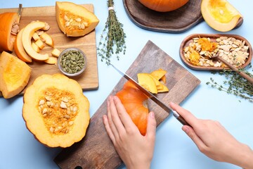 Woman cutting pumpkin on light blue background, above view