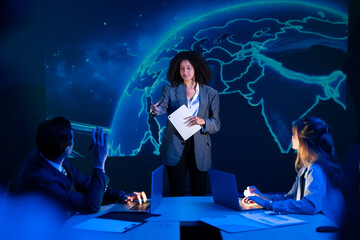Diverse business team in a meeting, with a female leader presenting a global strategy on a large screen.