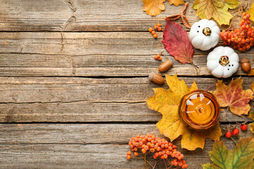 Dry autumn leaves, decorative pumpkins, acorns and berries on wooden table, flat lay. Space for text
