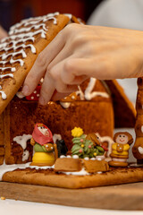 Woman hands building a gingerbread house at home. Christmas holiday preparation.