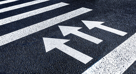 Pedestrian crossing with white marking lines and arrows on asphalt.