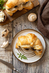Freshly baked croissants with mushrooms and ricotta on rustic wooden table setting. Top view flat lay.