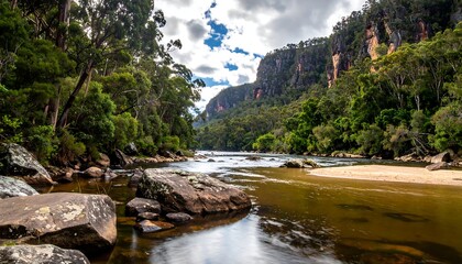 A tranquil scene of a river flowing through a gorge, flanked by lush green trees and dramatic cliffs under a cloudy sky