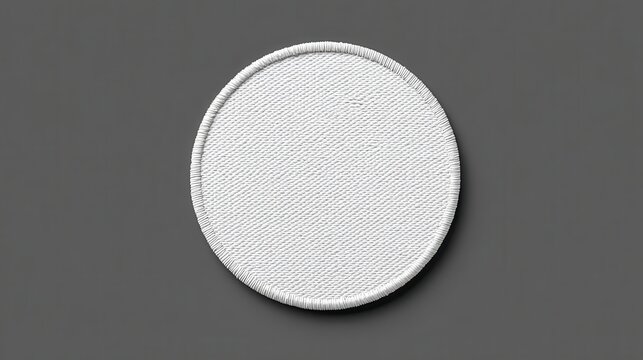 White circular fabric patch with textured surface on gray background