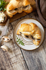 Freshly baked croissants with mushrooms and ricotta on rustic wooden table setting. Top view flat lay.
