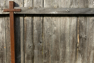 A rustic wooden fence with a cross made of metal. The wood is weathered and shows signs of age. The...