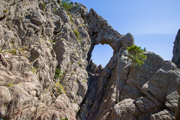 the bomb hole in the rock seen from a distance in the Bavella Mountains in the sunshine