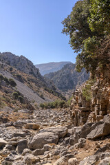 view of Ha Gorge (Hagvos Gorge) crevice in Crete, Greece. Rugged cliffs and rocky terrain form a dramatic mountain landscape, captured in bright Mediterranean sunlight. This natural landmark represent