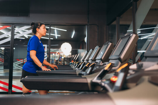 A motivated woman with a prosthetic leg walking on a treadmill in a modern gym, representing fitness, rehabilitation, and strength with a positive attitude towards an active healthy lifestyle.