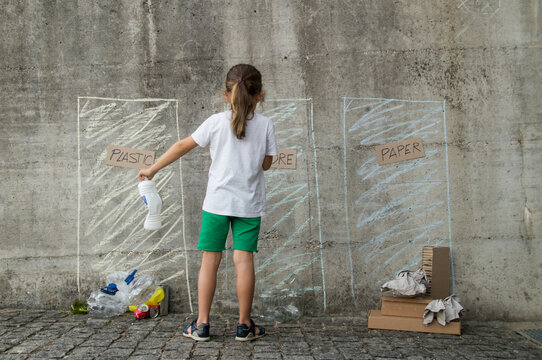 Long-haired blond boy in an outdoor environmental education class sorting plastics and recyclable containers - Powered by Adobe