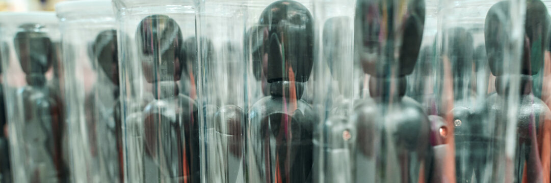 Rows of black mannequins encased in clear plastic cylinders for display in art installation. - Powered by Adobe