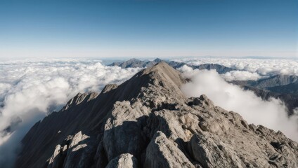 Obraz premium Rugged mountain peak emerges from sea of clouds under a clear blue sky, panoramic vista
