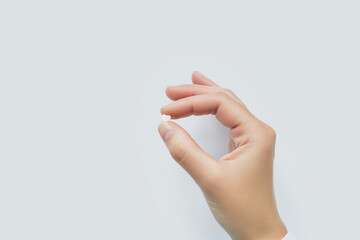 Hand holding a small white heart shaped pill