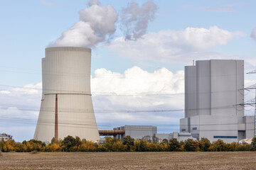 Massive cooling tower power plant Saxony  Germany releasing steam  cloudy sky. Industrial complex surrounded by fields illustrates modern energy generation, infrastructure environmental technology
