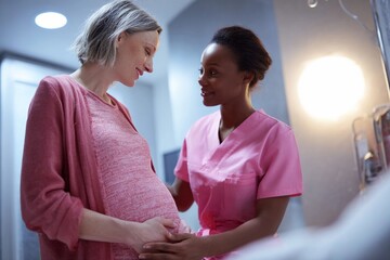 Caring nurse supports pregnant woman in hospital room during labor preparation