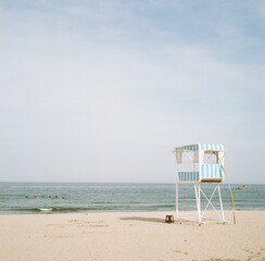 Minimal seaside scene with empty lifeguard tower and calm ocean under pale sky, photographed on Rolleiflex film