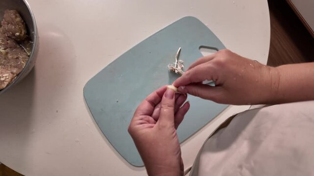 A woman peels garlic over a cutting board. The concept of cooking a dish.