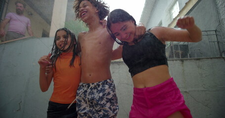 Children laughing and embracing under water during a backyard gathering, sharing joyful and...