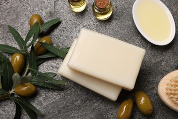 Flat lay composition with handmade soap bars, olives and oil on gray textured table