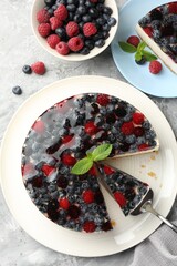 Taking piece of delicious cheesecake with berries at grey textured table, flat lay