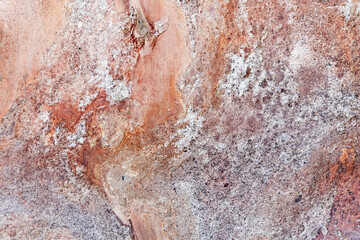 Close-up of a rugged rock surface featuring rust-orange hues, background texture