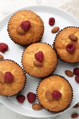 Fresh muffins with raspberries and almonds on table, top view