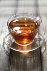 Aromatic black tea in glass cup on wooden table, closeup