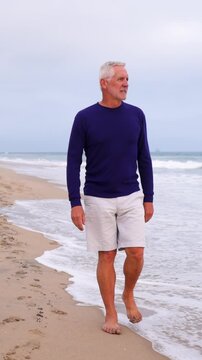 A mature 66 year old man jogging at the beach in Southern California. Slow Motion. Vertical Video.