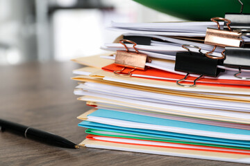 Many folders with documents and pen on wooden desk, closeup. Space for text
