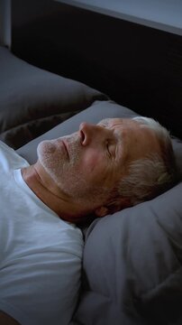 Mature adult sleeping at night. Vertical Video.