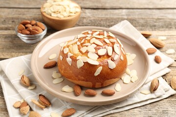 Tasty roll bun with almond flakes and nuts on wooden table, closeup