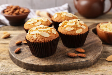Tasty muffins with almond flakes and nuts on wooden table, closeup