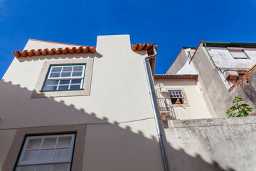A low-angle view captures whitewashed buildings with terracotta roofs against a vibrant blue sky
