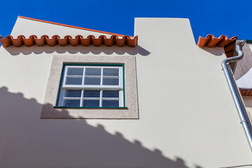A low-angle view captures whitewashed buildings with terracotta roofs against a vibrant blue sky