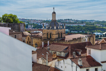 A panoramic cityscape showcases a historic building with a tiled dome rising above a sea of terracotta rooftops