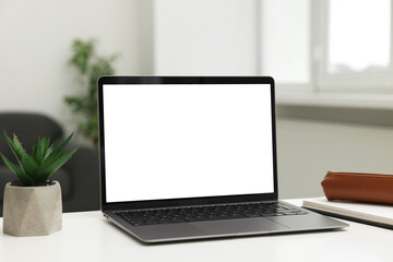 Fototapeta premium Laptop, notebook and plant on white desk indoors. Mockup for design