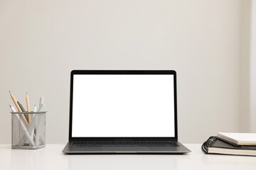 Fototapeta premium Laptop, notebook and stationery on white desk indoors. Mockup for design