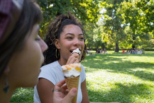Diverse friends enjoying ice cream in park - Powered by Adobe