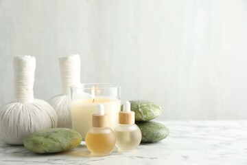 Beautiful spa composition with herbal bags and burning candle on white marble table, closeup. Space for text