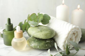 Beautiful spa composition with essential oils and eucalyptus on white marble table, closeup