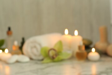 Blurred view of beautiful composition with spa products and burning candles on white marble table