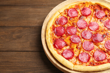 Delicious cut pepperoni pizza on wooden table, closeup. Space for text