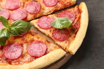 Delicious cut pepperoni pizza with fresh basil on grey table, closeup