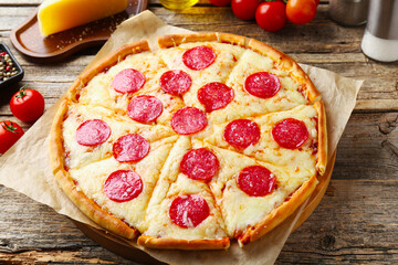Delicious pepperoni pizza and ingredients on wooden table, closeup