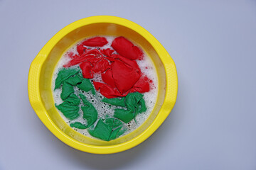 Plastic basin with clothes, water and foam on light grey background, top view. Space for text