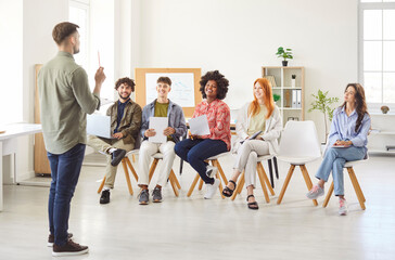 Businessman leads a meeting for a team of colleagues in the office. The people group engages in professional conversation, discussing business matters in a collaborative and work focused environment.