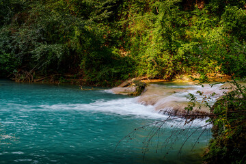 Obraz premium Turquoise mountain river waterfall in lush summer forest, vibrant scenic nature