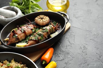 Tasty cooked squids with sauce, garlic and products on black table, closeup. Space for text
