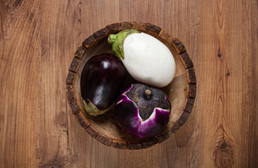 colored eggplant, in a wooden bowl, white, purple and black eggplant, top view, raw eggplant, no people,