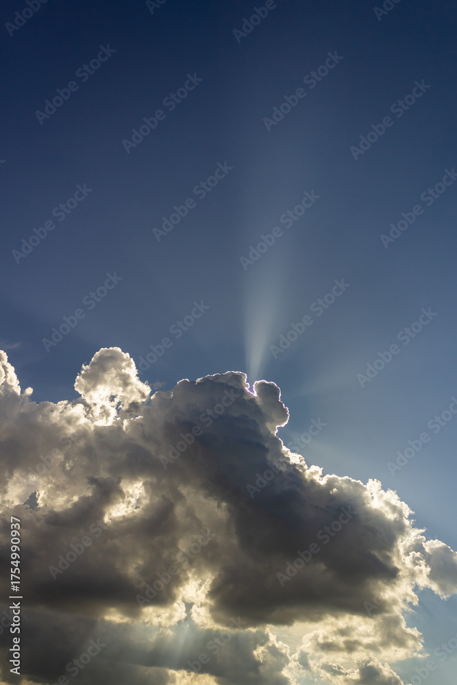 Wall mural clouds in the blue sky with sun rays and lens flare.
